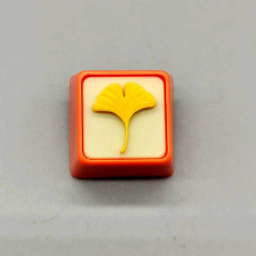 Close-up of a handcrafted artisan leaf keycap, showcasing delicate green leaves beautifully suspended in clear resin, evoking natures calm.