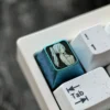 Multiple views of the Frieren titanium keycap, showcasing its ethereal ice crystal blue finish and premium titanium alloy craftsmanship from various design.