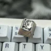 Multiple views of the hand-sculpted titanium Frieren keycap, revealing the precision-carved anime portrait and mirror-finish with intricate stippling.