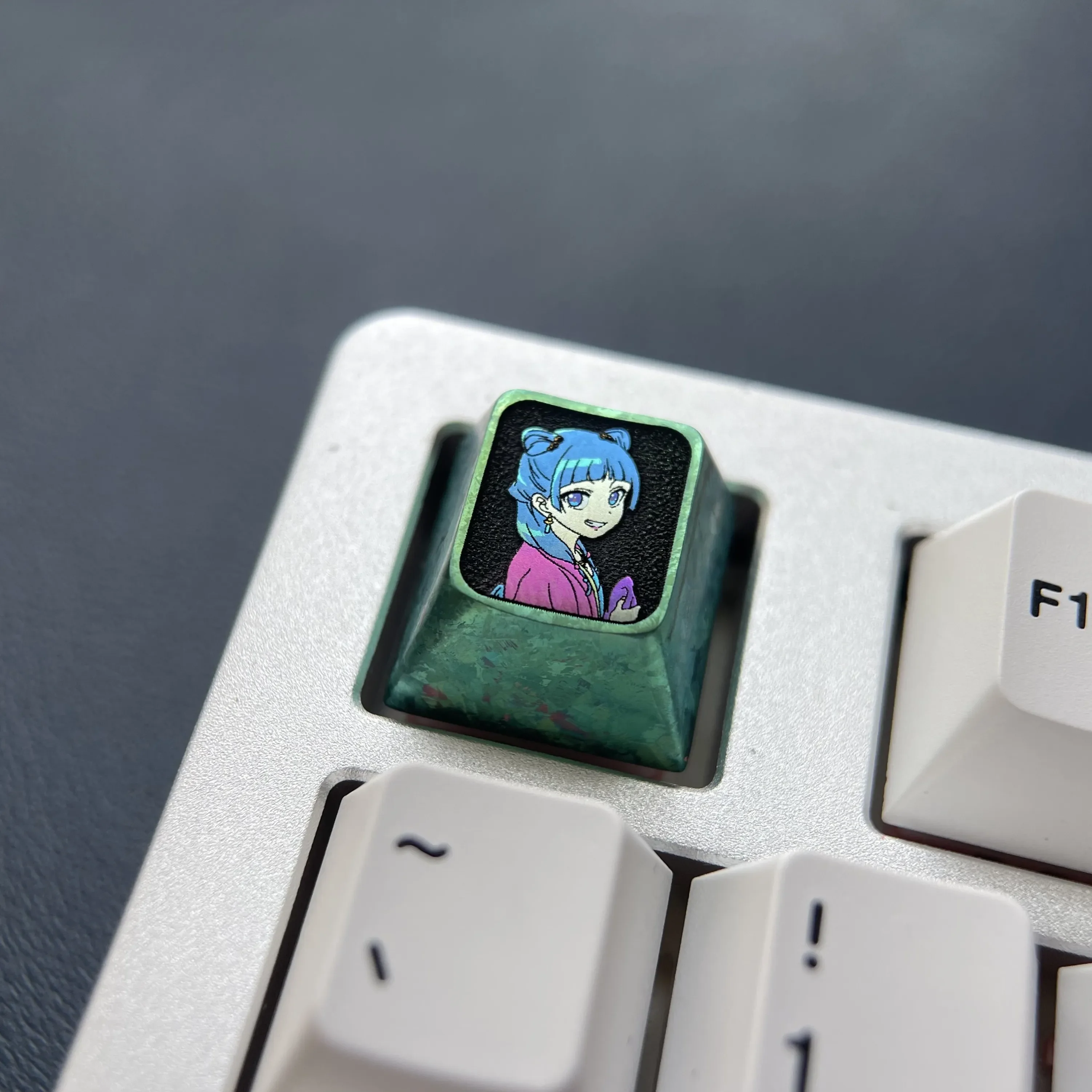 Multiple angles of the premium titanium Maomao Keycap, displaying its vivid anime cat motif and polished metallic finish with fantasy charm.