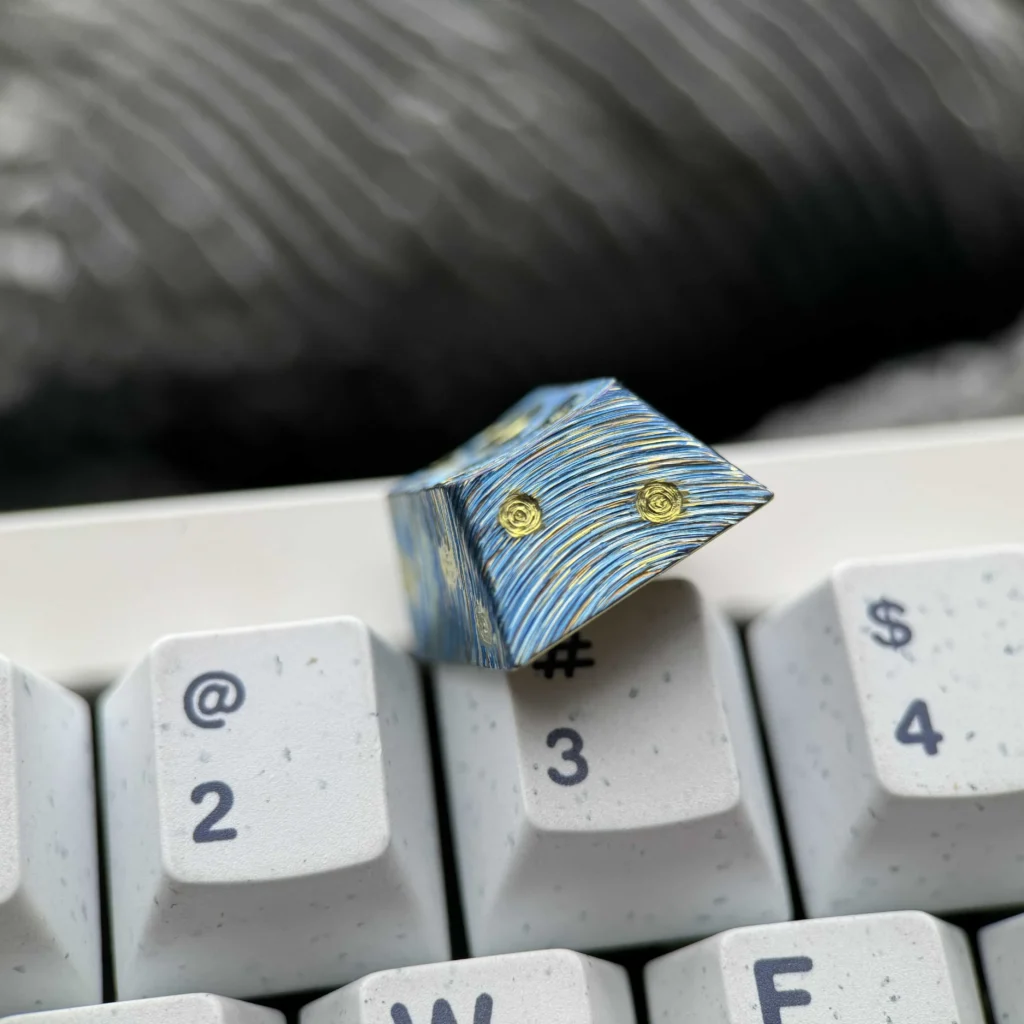 Hand-carved titanium Starry Night keycap gallery. Shows Van Gogh celestial landscape, relief, metallic sheen, all angles.
