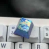 Handcrafted titanium artisan keycap with an abstract mountain design in vibrant metallic colors, captured from multiple angles.