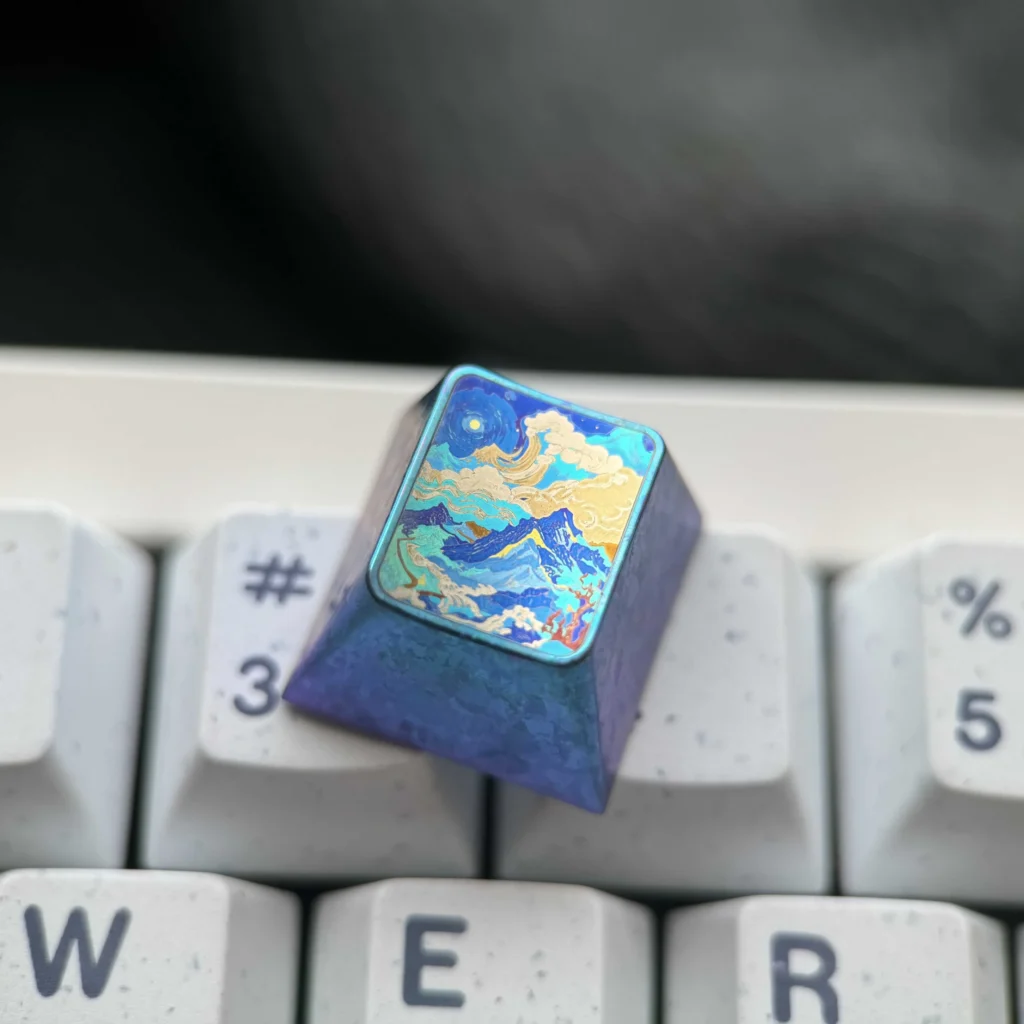 Handcrafted titanium artisan keycap with an abstract mountain design in vibrant metallic colors, captured from multiple angles.