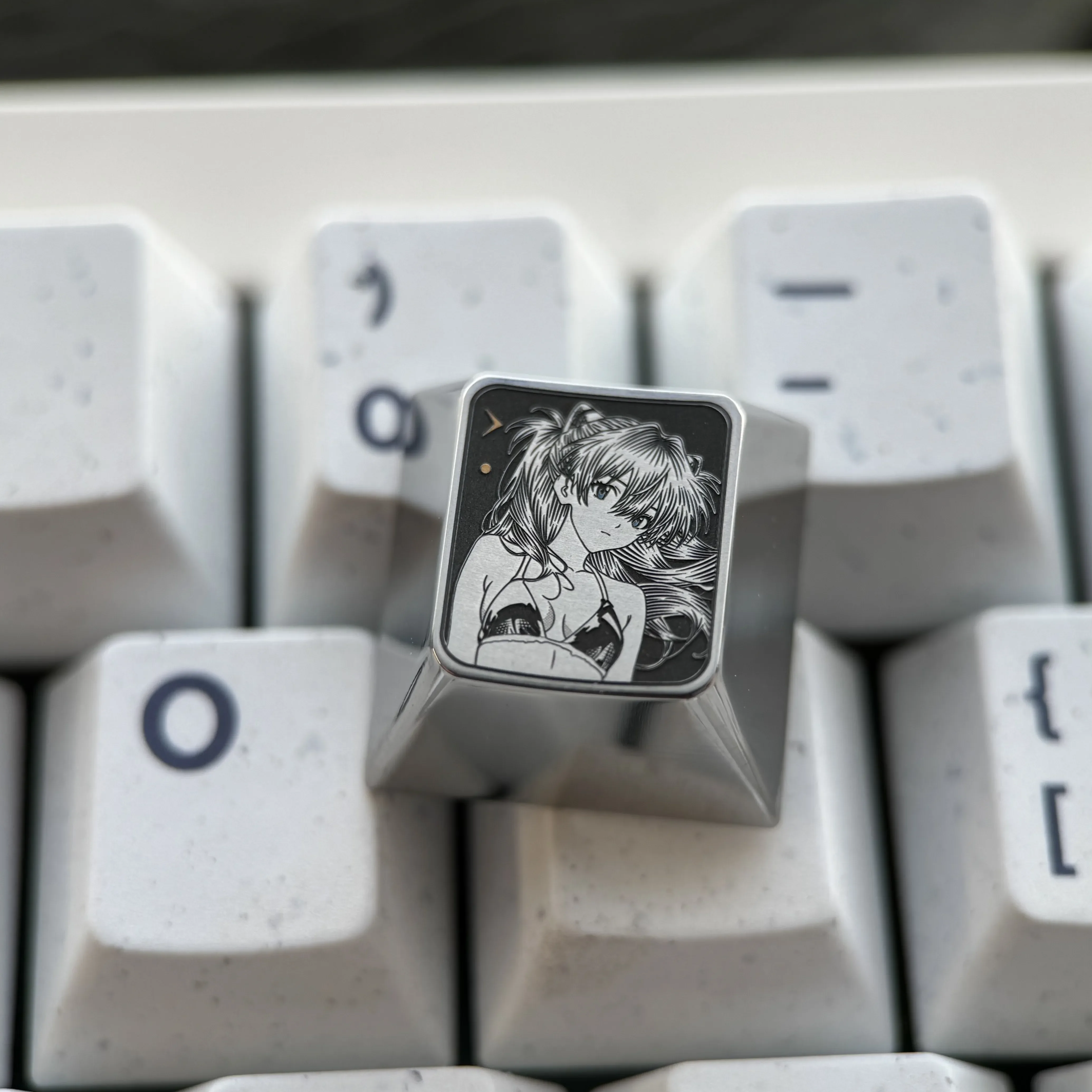 Close-up of the premium Asuka titanium alloy keycaps, showcasing its vibrant sci-fi anime art and precision engraving for Evangelion fans.