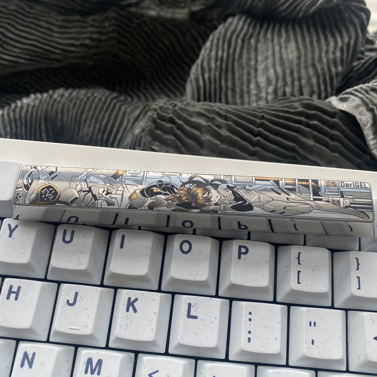 A vibrant, precision-engraved Asuka Titanium 7U Spacebar keycap, displaying intricate anime mecha artwork on its premium metallic surface.