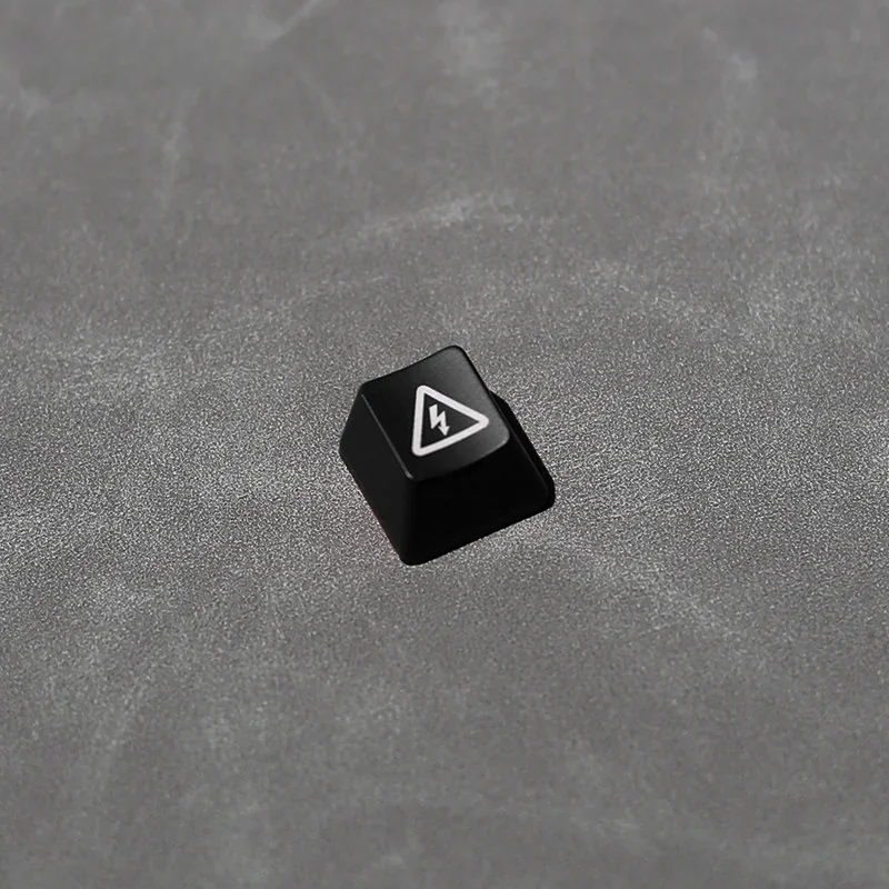 Close-up of a black Electric Hazard danger keycap, featuring a striking backlit red and yellow industrial warning symbol. Edgy, high-contrast design.