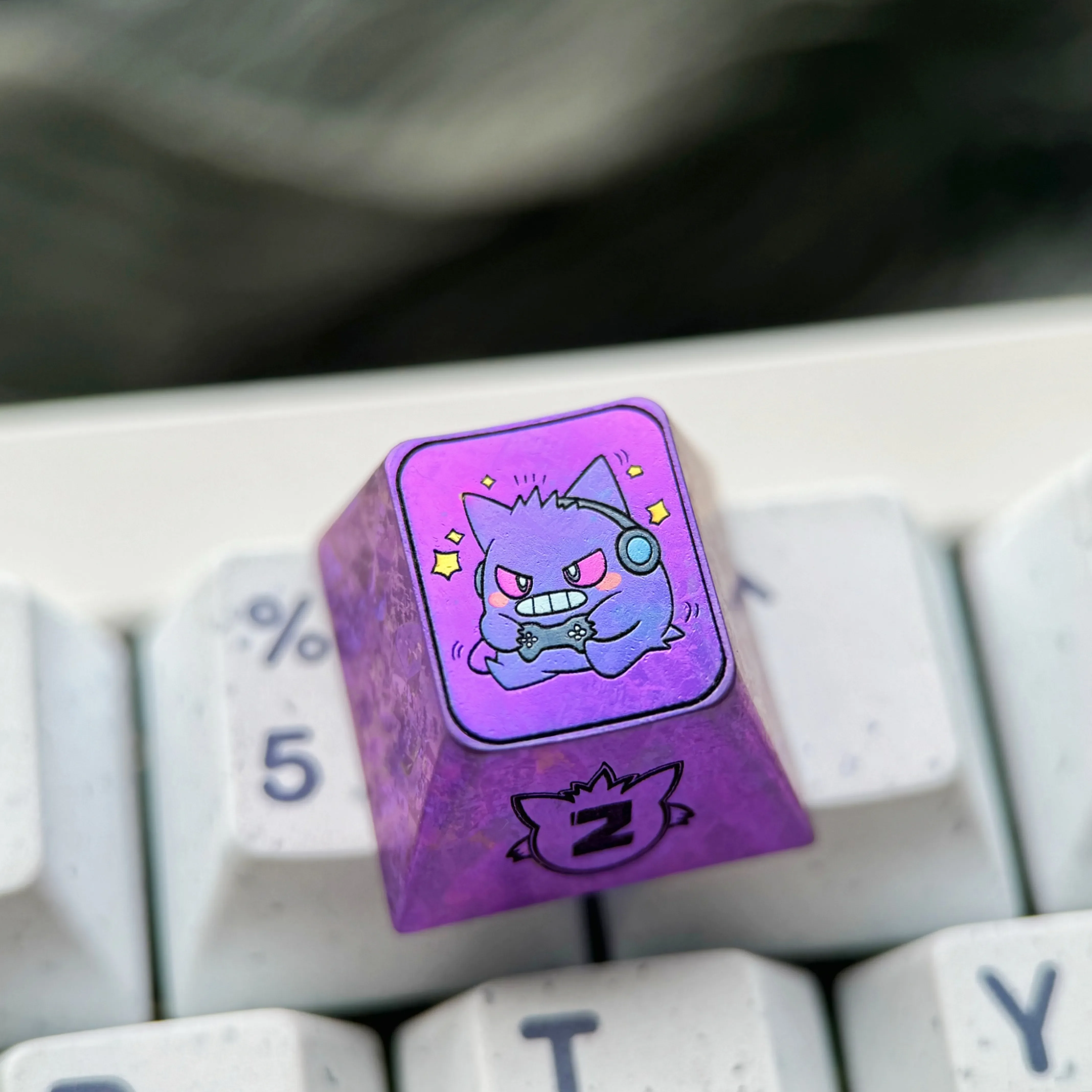 Premium titanium alloy Gengar artisan keycap displayed on a mechanical keyboard, showcasing its stylized metallic purple finish and high-quality setup.
