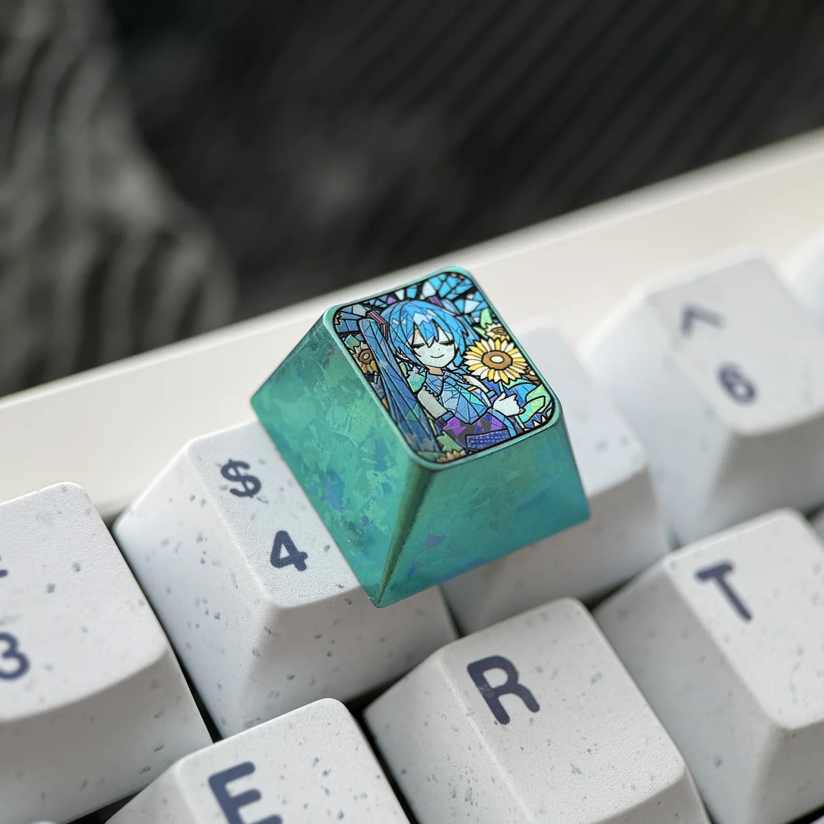 Close-up views of the Hatsune Miku titanium keycap, showcasing its vibrant anime design, sunflower motif, and rich green accents from various angles.