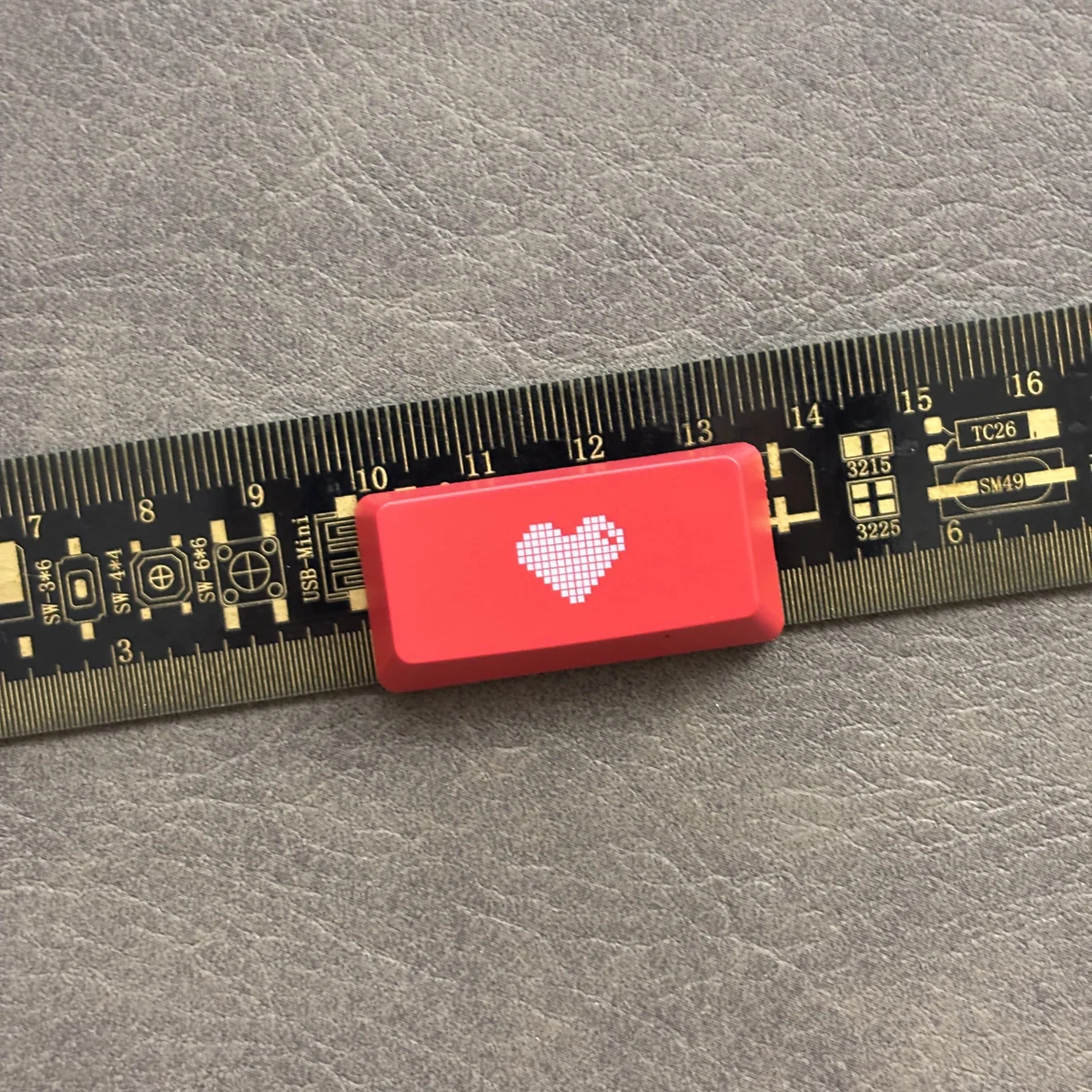 A premium Double-Shot ABS Backlit Heart Keycap, viewed from a slight angle, showcasing its glowing red translucent heart on a sleek red design.