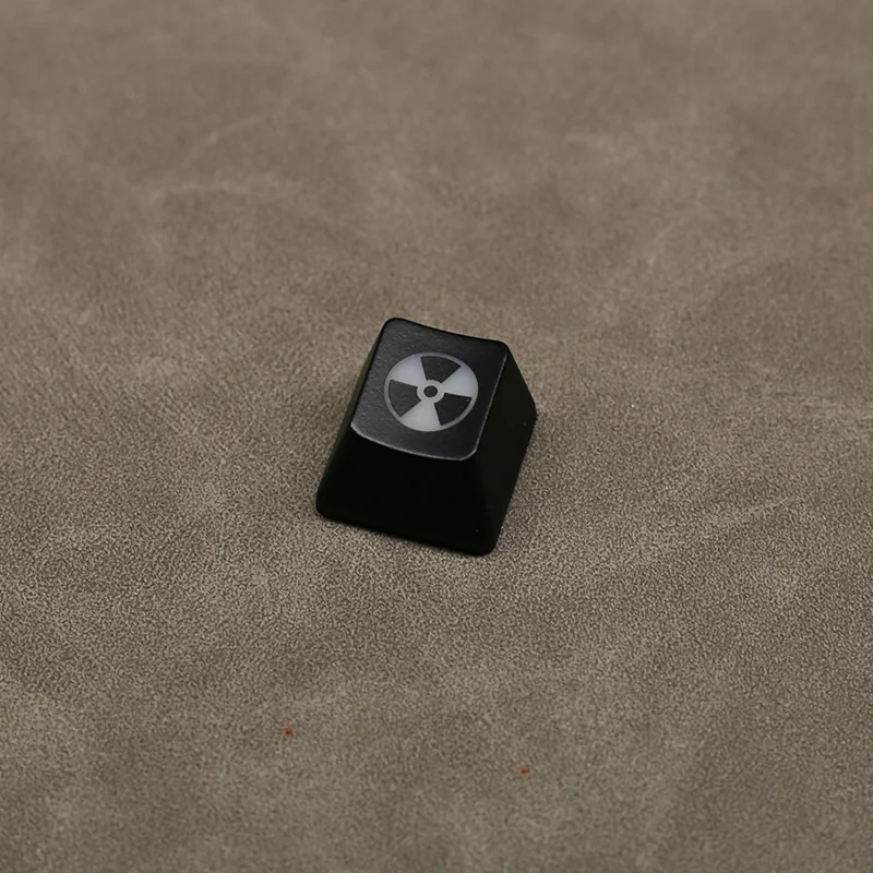 Edgy black ABS nuclear hazard keycap displayed from various angles, highlighting its unique backlit translucent radiation symbol and premium craftsmanship setup.