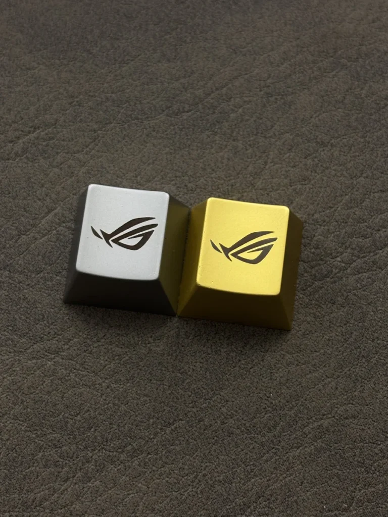 Close-up of the iconic Republic of Gamers: ROG Logo Alloy Keycaps, featuring its aggressive angular design and a premium metallic finish. Elevate your gaming keyboard.