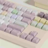 A whimsical gallery of Taro Pistachio Keycaps Set showcasing their sweet pastel purple, green, and cream dessert-inspired aesthetic from various angles.