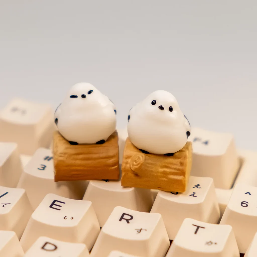 Handcrafted whimsical Bushtit artisan keycap showcasing its adorable 3D sculpted form from a charming front-side perspective on a rustic log.