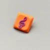Handcrafted Treble Clef Low Shaft Keycaps featuring a vibrant resin treble clef on a playful orange base. This unique musical note MX keycap enhances any keyboard.