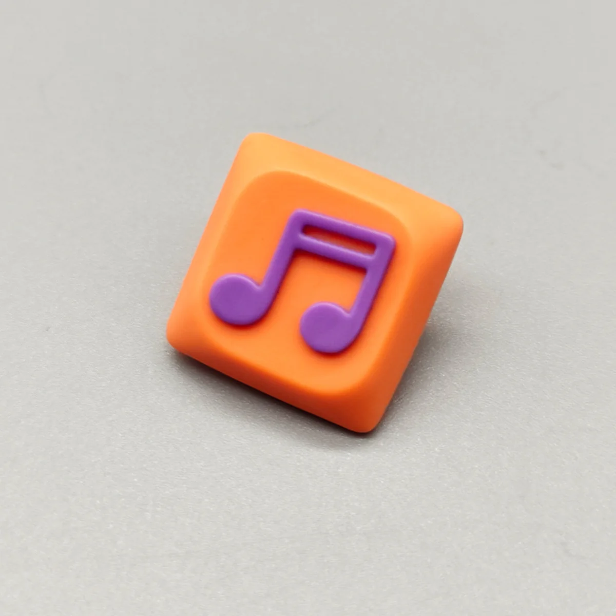 Handcrafted Two Beam Eighth Note Symbol Keycaps featuring a vibrant orange translucent resin base and an embedded rhythm symbol, showcasing artistic flair.