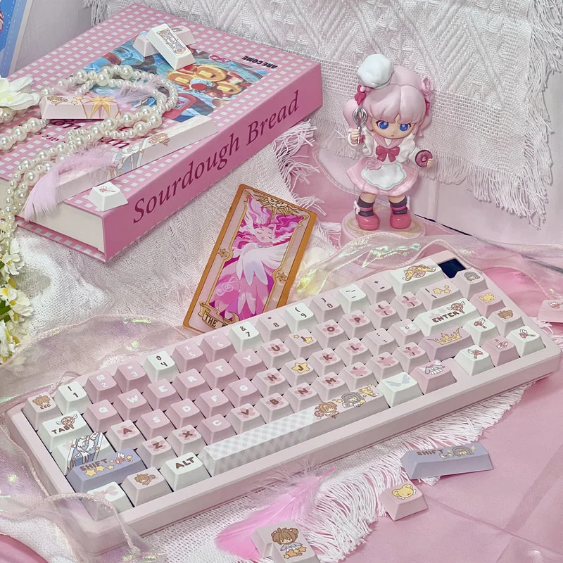 Iconic Cardcaptor Sakura PBT dye-sub keycaps set in playful pastel pink and white, packaged in a box with a keycap puller, capturing magical anime charm.