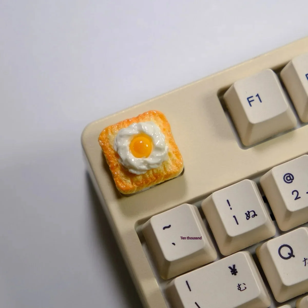 Close-up gallery of the whimsical handcrafted 3D fried egg toast artisan keycap, showcasing its vibrant yellow yolk and crisp white toast from multiple angles.