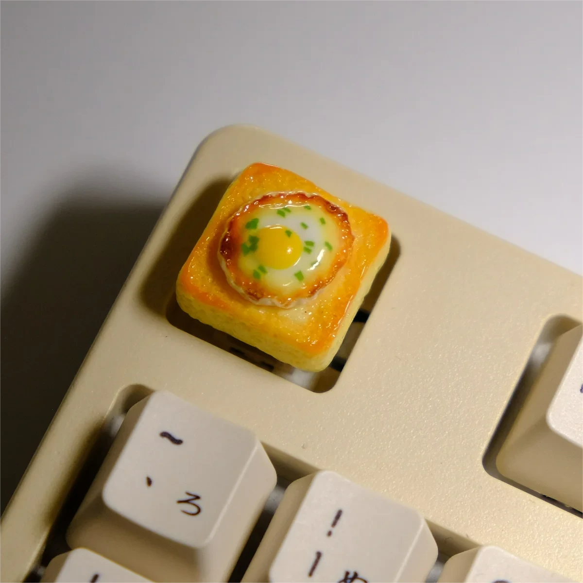 Playful handcrafted 3D miniature fried egg toast artisan keycap, captured from various angles to reveal its vibrant yellow and white details.