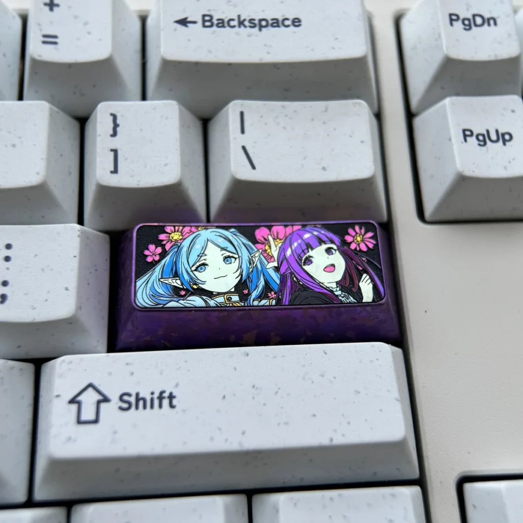 Premium Frieren & Fern titanium artisan keycap, showcasing vibrant character art on polished metal. A high-quality collectible Frieren keycap.