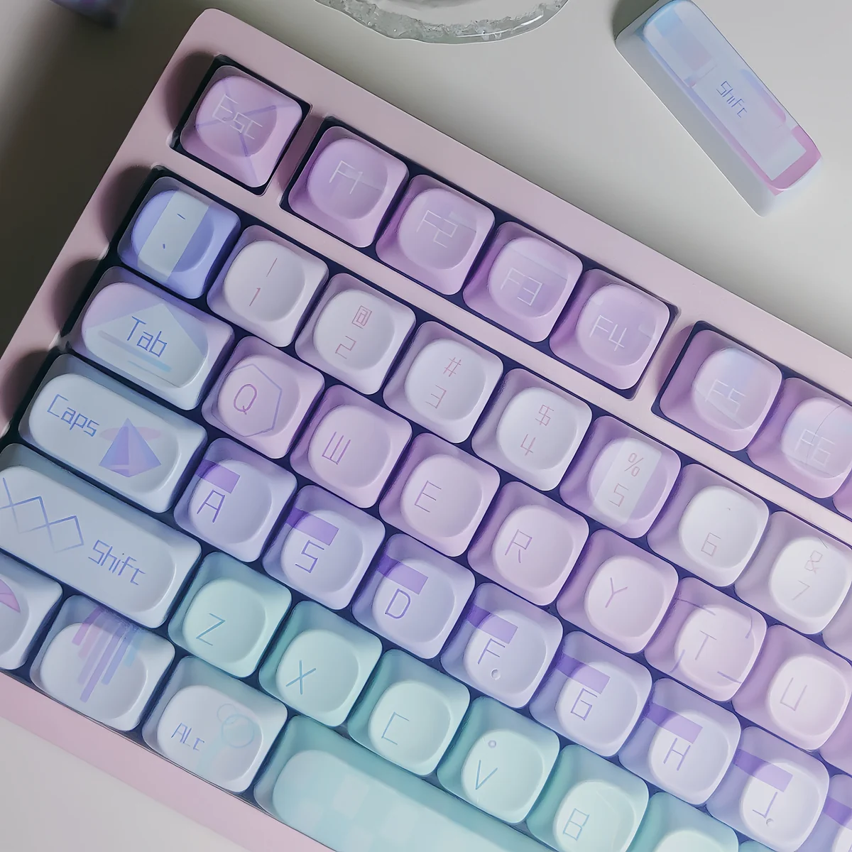 Artistic close-up of vibrant Geometric Gradient Keycaps Set, revealing the serene pink-blue PBT material and crisp geometric patterns for a modern desktop.
