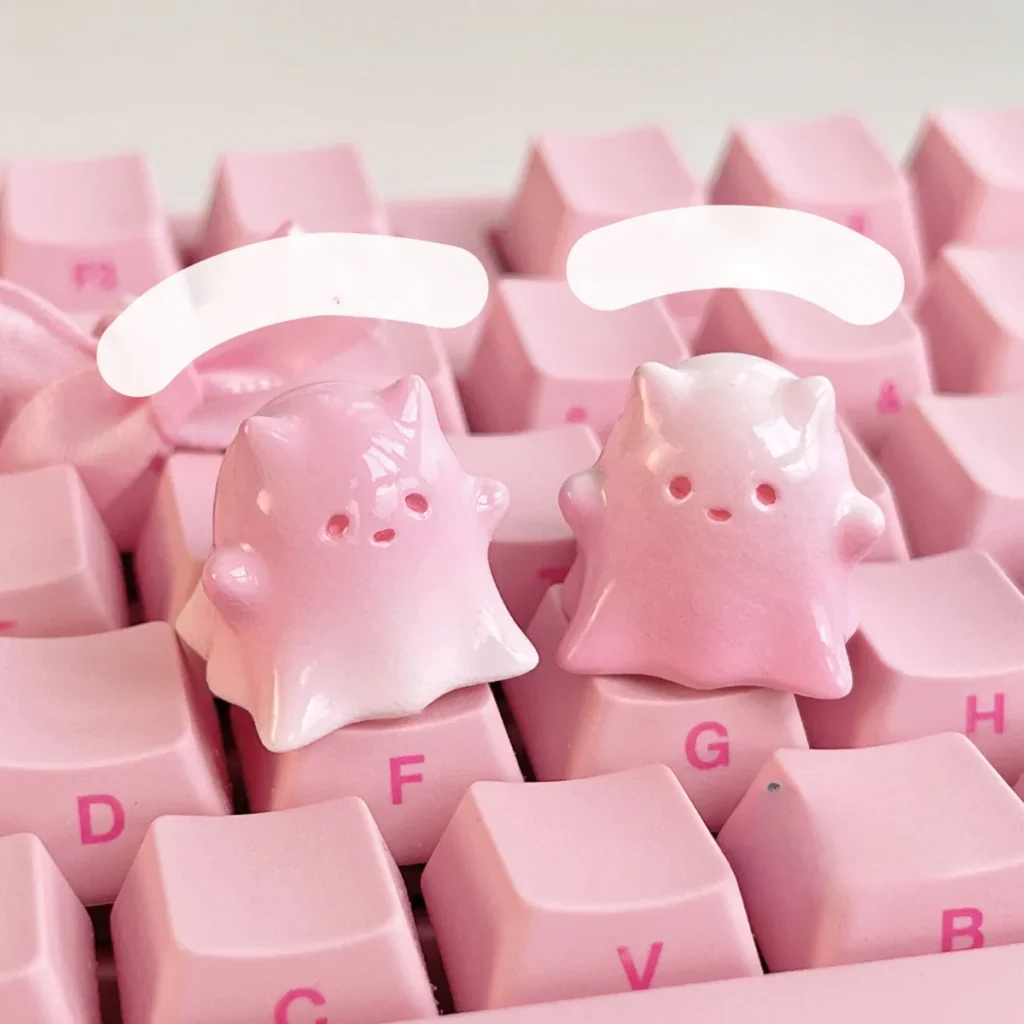 Close-up of a whimsical hand-painted resin ghost cat keycap, showcasing its ethereal pink and white pastel gradient art.