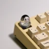 A cute handmade artisan glowing No-Face keycap, featuring its whimsical translucent 3D design and ethereal glow from different angles on a mechanical keyboard.