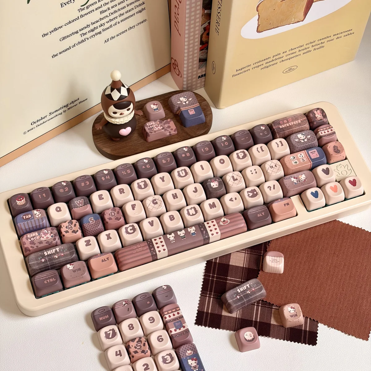 Exclusive Hello Kitty Mont Blanc dessert keycaps set in warm creamy browns and whites, showcasing the playful design from various cozy angles.