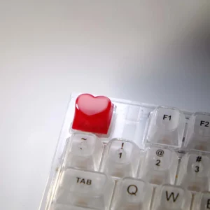 Radiant 3D red heart keycap glowing with vibrant light, showcasing its sculpted design and translucent finish for backlighting.