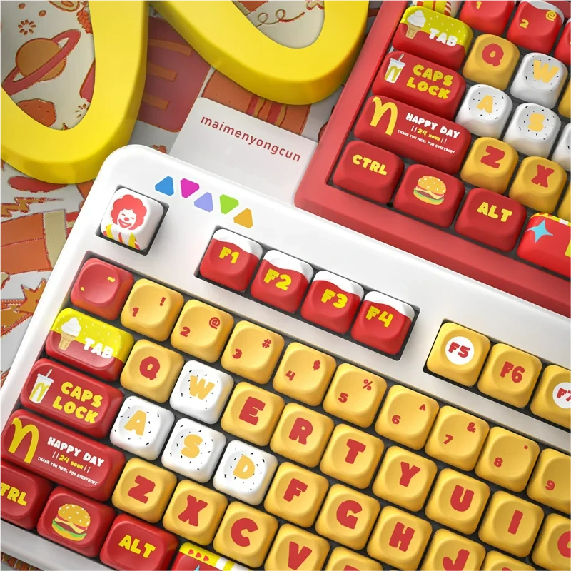 A playful set of McDonald's MOA PBT keycaps set displayed from various angles, showcasing vibrant red, yellow, and white colors with iconic fast-food design.