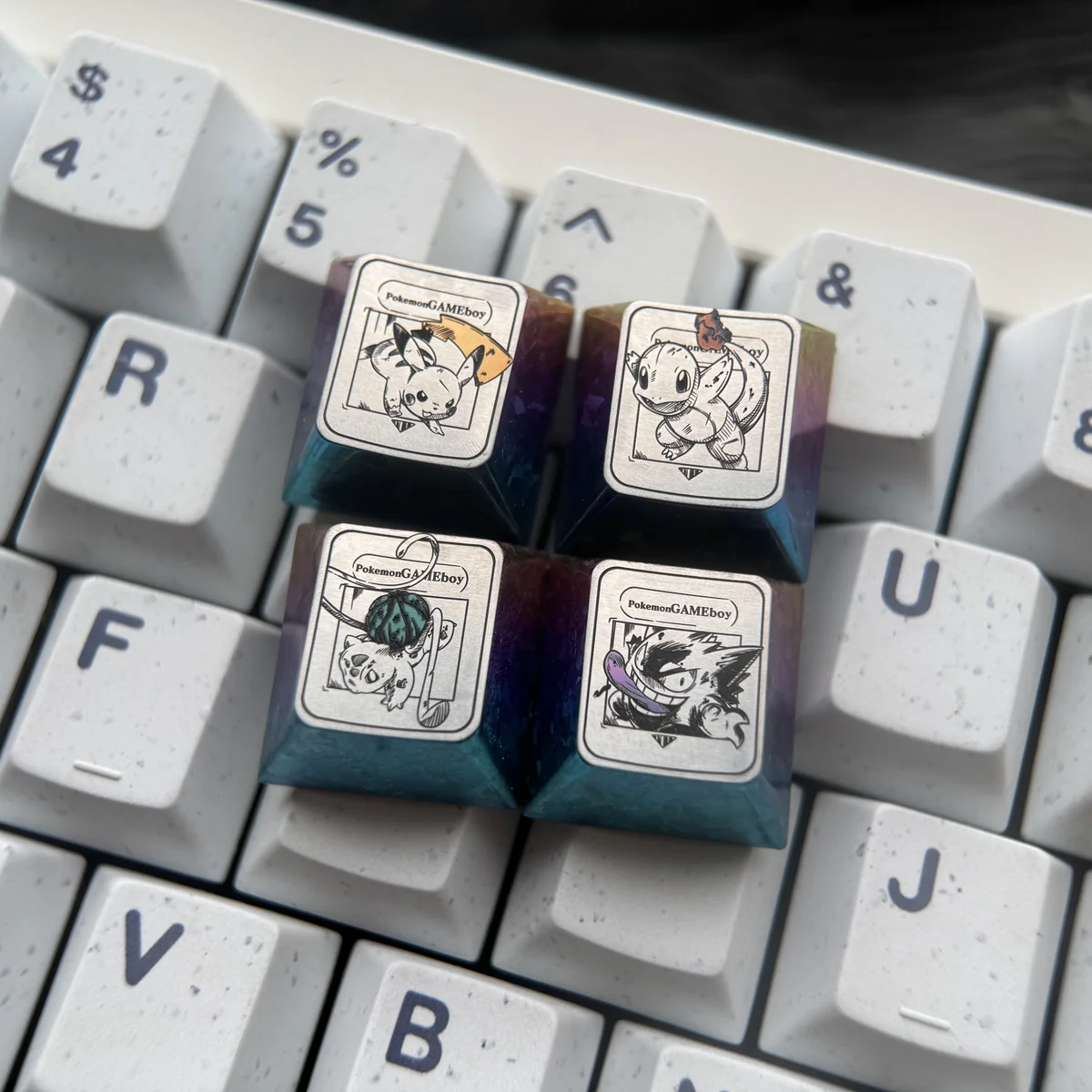 Close-up of a premium Characters Titanium Pokemon artisan keycap, showcasing its iridescent finish and intricate sculptural details from multiple angles.