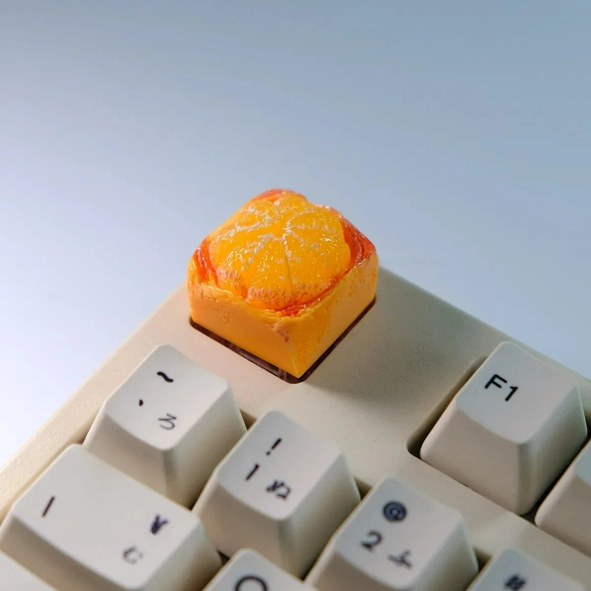 Angled shot of the whimsical orange artisan keycap, revealing its vibrant, hand-sculpted miniature fruit detail for keyboards.