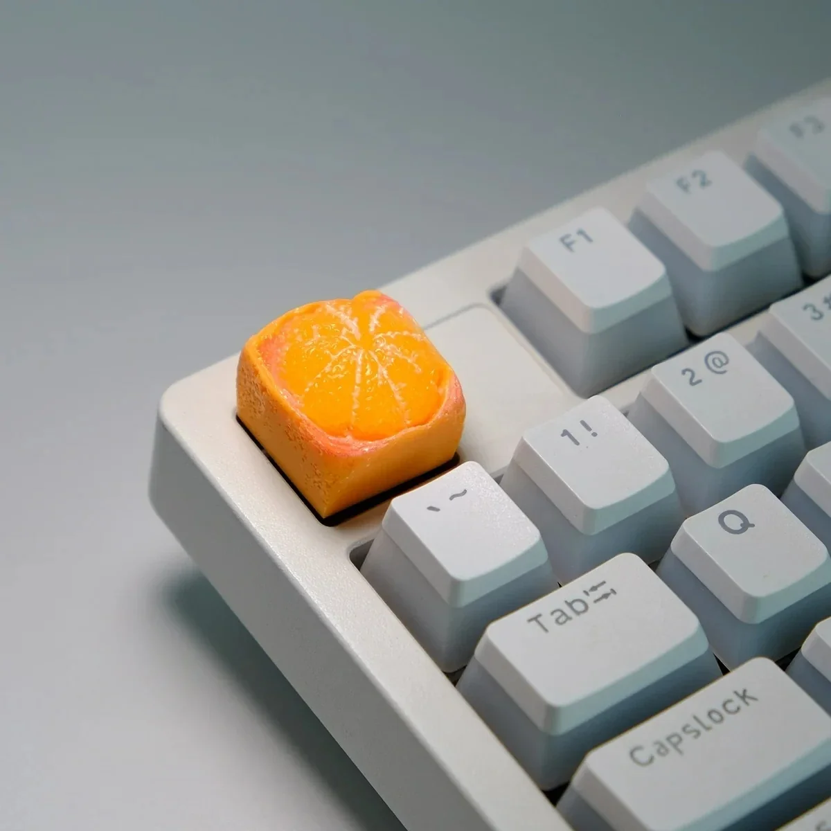 Close-up of a handcrafted, whimsical orange artisan keycap for keyboards, showcasing its vibrant miniature fruit design from multiple angles.