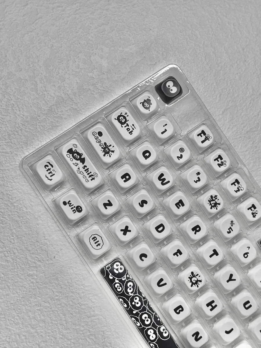 A gallery of whimsical Ghibli Susuwatari PBT Dye-sub keycaps set, showing enchanting characters from multiple angles against a minimalist backdrop.