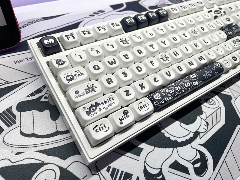 A gallery of whimsical Ghibli Susuwatari PBT Dye-sub keycaps set, showing enchanting characters from multiple angles against a minimalist backdrop.