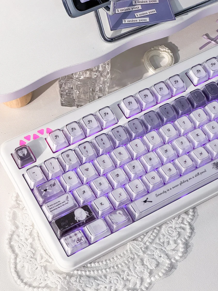 Close-up views of the handcrafted Ethereal Swan Realm Keycap Set, showcasing its translucent amber and deep purple layers from various angles.