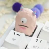 Unique handcrafted artisan resin keycap from various angles, showcasing a whimsical vibrant little monster creature embedded in colorful design.
