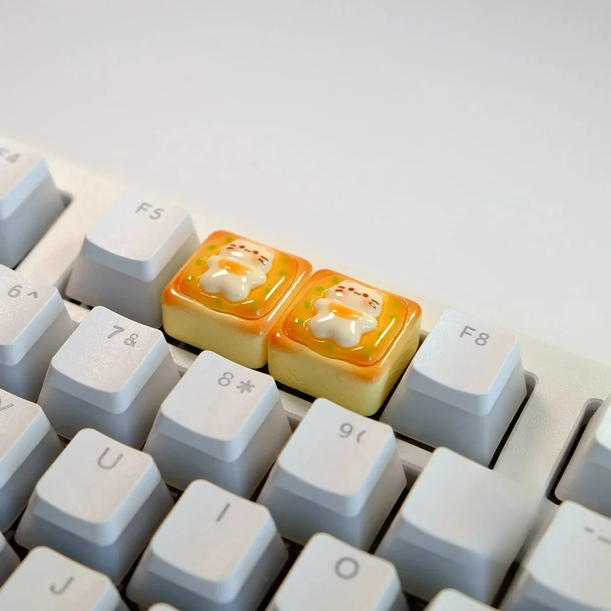 Side view of the handcrafted whimsical cat toast keycap, showcasing the adorable sleepy cat nestled on golden toast, a unique keyboard charm.