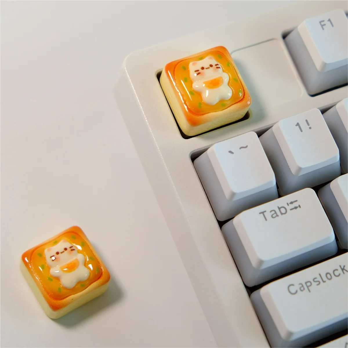 Another angle of the adorable handcrafted cat toast keycap, highlighting the sleepy feline nestled on golden toast. A whimsical artisan keyboard charm.