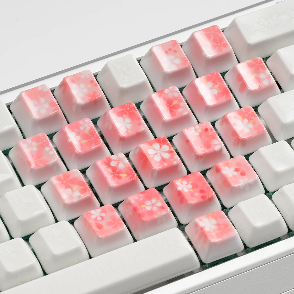 Artisan keyboard keycaps with cherry blossom and butterfly motifs on translucent ceramic.