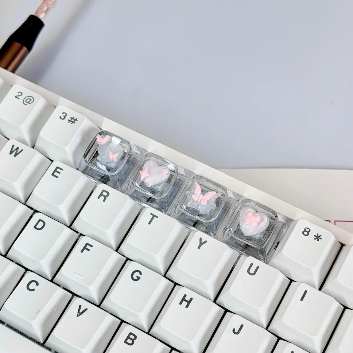 Hand holding a single Pink Butterfly Heart keycap, showcasing the delicate craftsmanship and vibrant pink hues