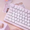Close-up of pastel pink PBT keycaps with dye-sublimated legends, highlighting the smooth texture and color accuracy.