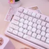 A whimsical keyboard setup featuring the Sweet Milk Candy keycaps, a matching desk mat, and other pastel accessories.
