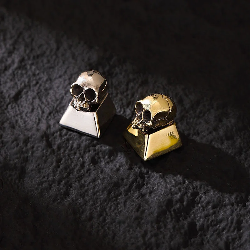 Side view of a cupronickel skull artisan keycap, highlighting its profile and metallic sheen.