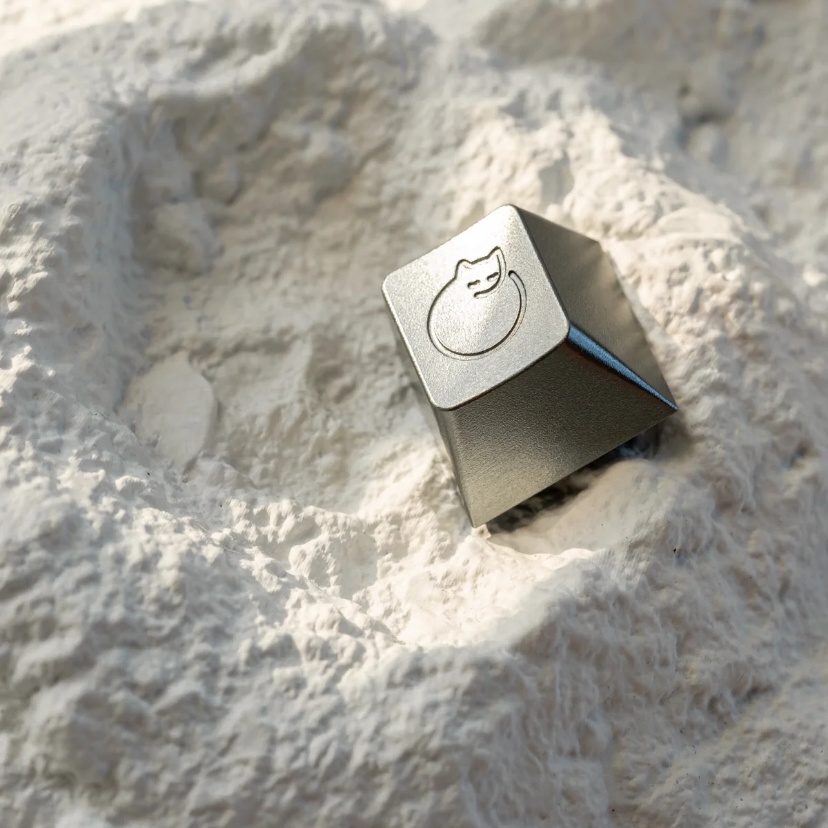 Close-up of handcrafted aluminum sleeping cat keycap detail