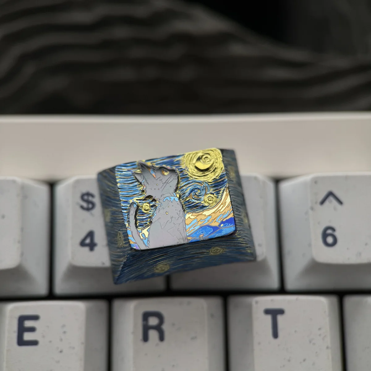 Close-up of handcrafted titanium keycap with black cat silhouette and starry background