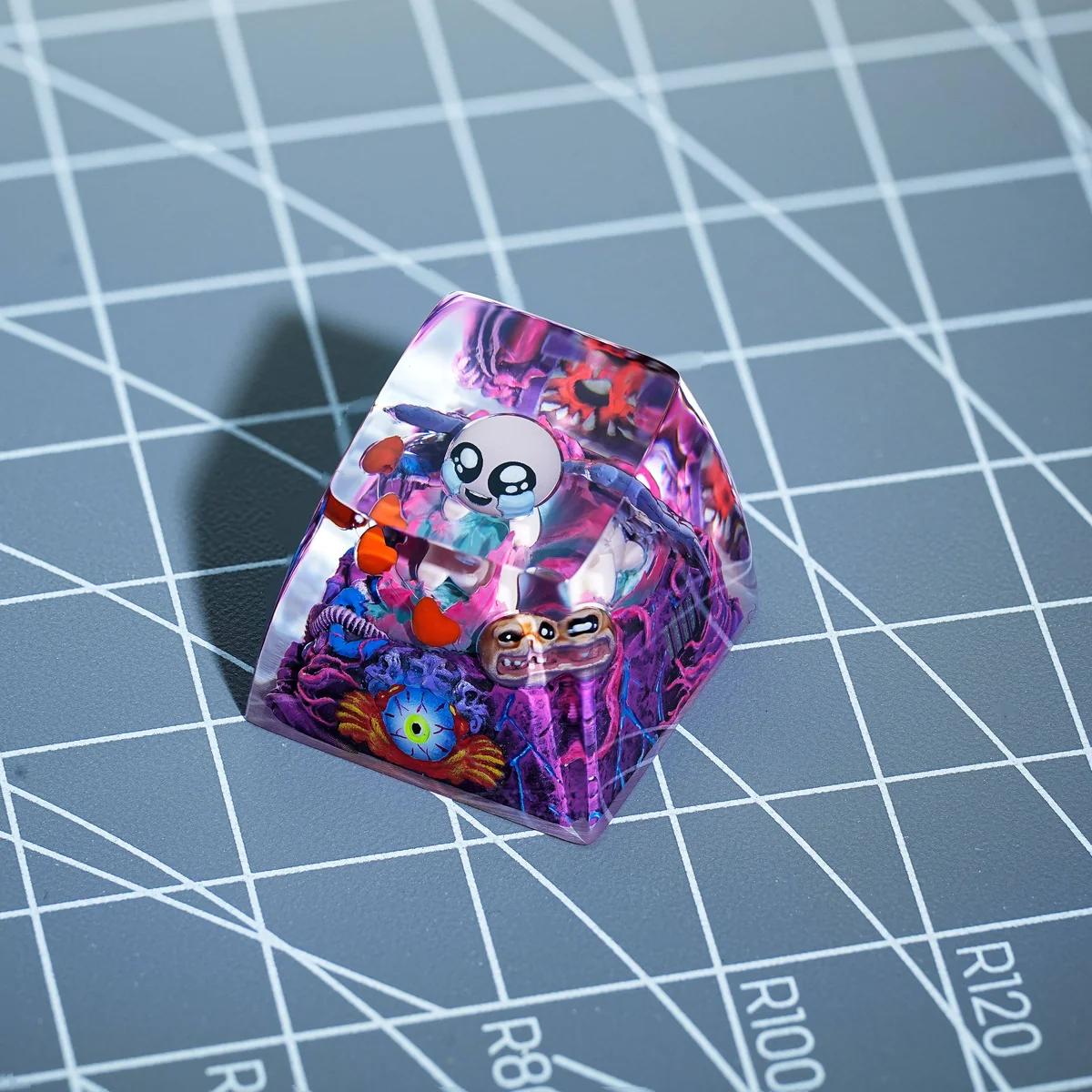Close-up detail of The Binding of Isaac character art on the transparent resin keycap, showing meticulous craftsmanship.
