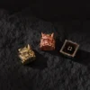 Collection of Oni Warrior keycaps in copper, white copper, and brass.