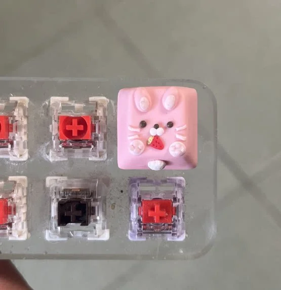 White and pink rabbit keycaps side by side showing hand-painted pastel finish and 1u size
